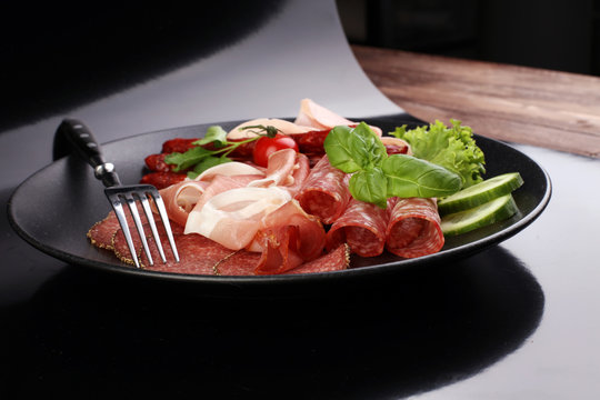 Food tray with delicious salami, pieces of sliced ham, sausage,