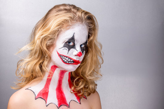 Portrait d'une jeune fille blonde maquillée en joker avec un faux sourire