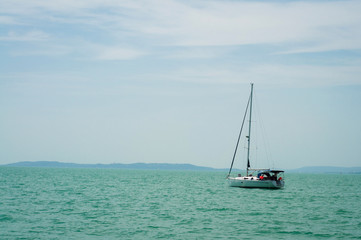 A sailboat is waiting in day stillness under beautiful blue sky with clouds on Lake Balaton,...