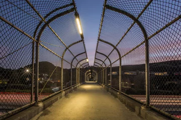 Foto op Plexiglas Brug der Zuchten Pedestrian Footbridge with Long Exposure of US 101 Traffic Lights During Sunset in Agoura Hills, Los Angeles County