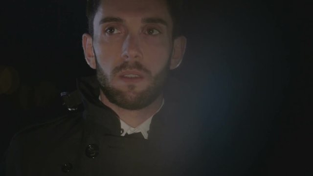 Uomo che guarda impaurito di notte in un parcheggio abbandonato 