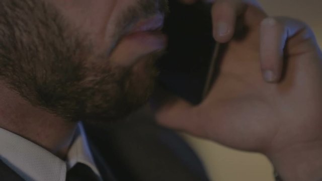 uomo in giacca e cravatta che parla al telefono