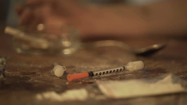 Hand of man suffering drug addiction lying on shabby table at cheap motel room