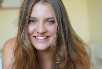 portrait of a young beautiful smiling girl with green eyes and long blond hair 	