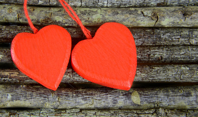 Pair of wooden hearts on rustic wooden background. The hearts are painted red. Plenty of copy space on the heart or on the background. Perfect romantic image for Valentine''s Day in February