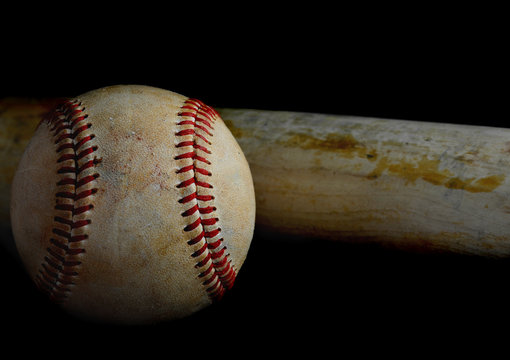 Low key image of old baseball and bat showing pine tar residue on black background.