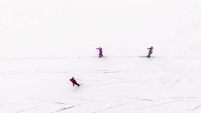 Top view at the three skiers running on snowy ice of frozen lake. Side view, camera tracking