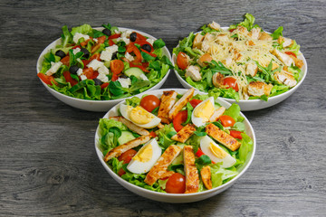 Caesar, greek and grilled chicken salad with lettuce, tomatoes and eggs