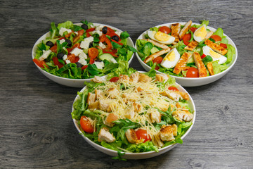 Caesar, greek and grilled chicken salad with lettuce, tomatoes and eggs