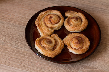 Cinnamon rolls buns on plate on wood.
