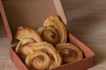 Cinnamon rolls buns in gift box on wood. Christmas surprise.