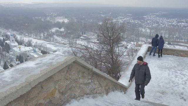 a Middle Aged Man Looking at Sviatogorsaya Lavra, and Climbing a Staircase of the Observation Deck of Artyom Monument, Located in Ukraine, in Winter