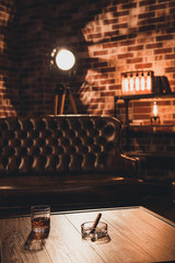 Loft interior. Leather couch with glass of whiskey and cigar on