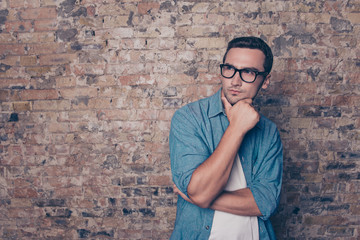 Portrait of minded man in glasses  on brick wall background