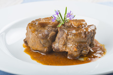 Guiso de carne de rabo de toro o ternera con salsa de verduras y vino tinto decorado con flores de romero para la comida
