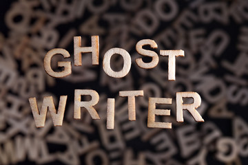 Ghostwriter text in wooden letters floating above random letters out of focus