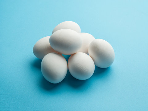 White chicken eggs on the blue background.