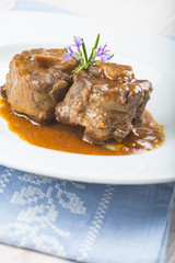Guiso de carne de rabo de toro o ternera con salsa de verduras y vino tinto decorado con flores de romero para la comida