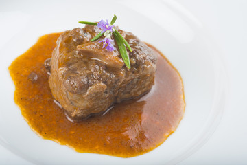 Guiso de carne de rabo de toro o ternera con salsa de verduras y vino tinto decorado con flores de romero para la comida