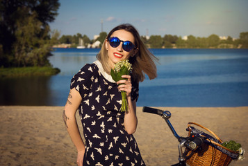 Beautiful young woman on the beach with bicycle and flowers