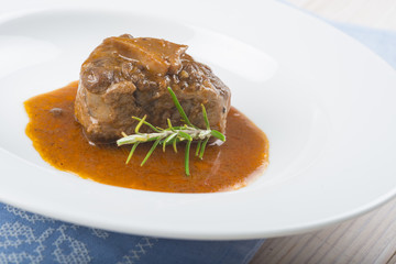 Guiso de carne de rabo de toro o ternera con salsa de verduras y vino tinto decorado con flores de romero para la comida