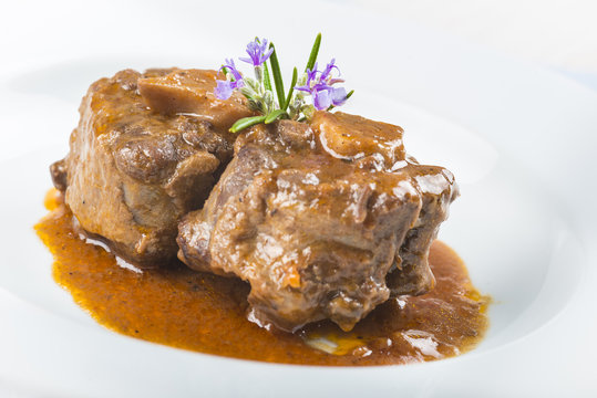 Guiso de carne de rabo de toro o ternera con salsa de verduras y vino tinto decorado con flores de romero para la comida