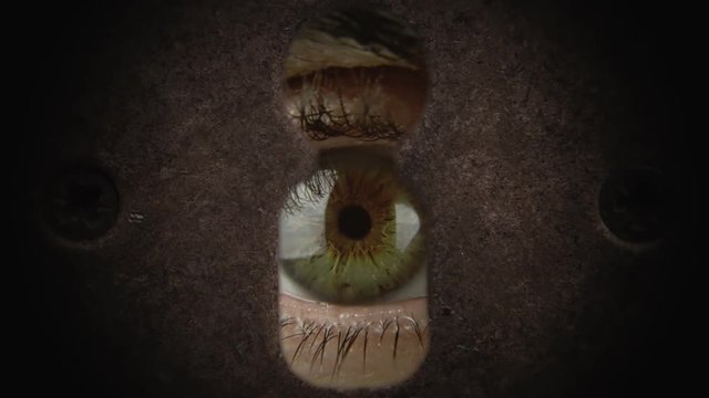 An angry eye spying from a keyhole. Concept: spying, surveillance, stalking.
