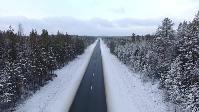 Back flying over empty northern highway in wintry evergreen forest. The Kola route in Karelia republic. Russia
