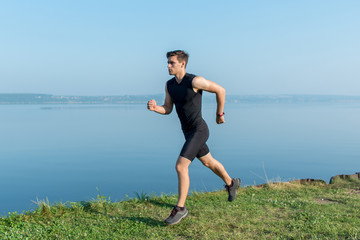 Athlete running man jogging on beach. Morning workout in summer