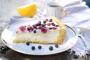 Sunny Photo with a morning breakfast in a rustic style. Cheesecake with raspberries and blueberries on wooden table. Selective focus picture
