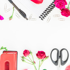Workplace with notebook, clips, red flowers, pen and scissors. Flat lay composition for blog. Top view.