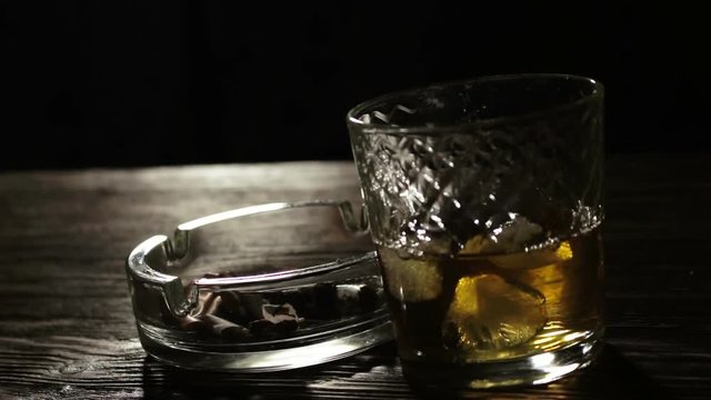Ashtray With Smoking Sigarette and Glass of Whiskey