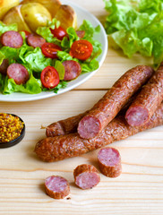 Sausage with vegateble salad on a wooden board