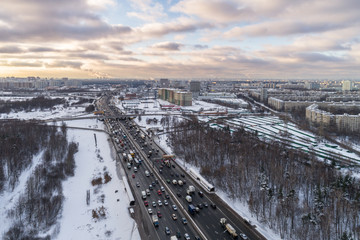 Cars traffic on direct highway at sunny winter frosty morning in the city. Urban cityscape. Flying forward. Aerial view.