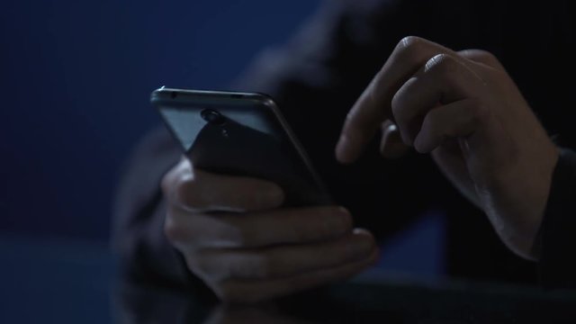 Man typing message on smartphone, wasting time at night party, hands closeup