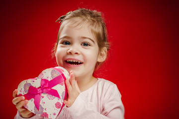 small and pretty girl holding a gift in the shape of heart