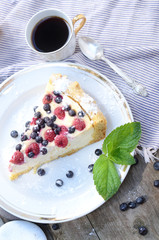 Sunny Photo with a morning breakfast in a rustic style. Cheesecake with raspberries and blueberries on wooden table. Selective focus picture