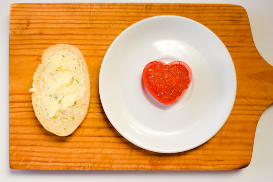Red caviar in a heart shape on white plate background