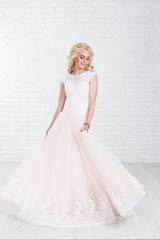 High fashion shot of young blond woman in white dress on  background.