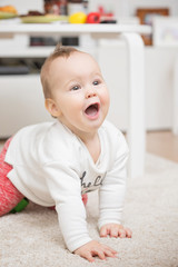 Nine months old baby girl playing crawling on the floor carpet