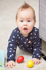 Nine months old baby girl playing with her toys on the floor, by