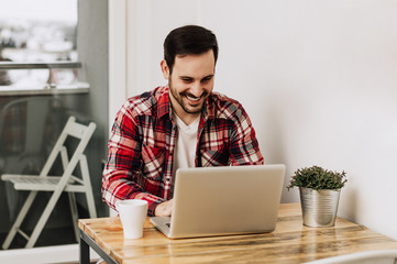 Young happy designer working on laptop from home