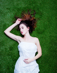 Portrait of a young redhead woman lying down on green spring gra © Masson