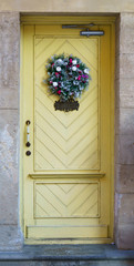 Vintage house yellow wooden planks door with Christmas wreath and inscription welcome. Vertical background.