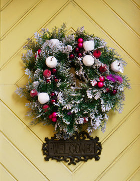 Christmas wreth and inscription welcome on yellow wooden planks rhombus surface. Vertical background..