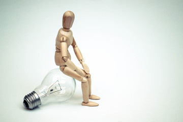 Wood Figure Mannequin sit on incandescent light bulb and think  