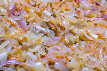 White and red onions in a frying process. Background