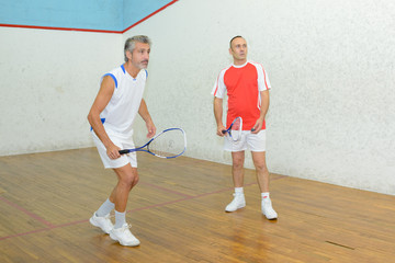 squash players in action on a squash court