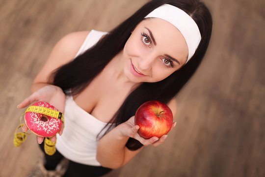 Diet. Dieting concept. Healthy Food. Beautiful Young Woman choosing between Fruits and Sweets