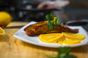 grilled salmon lying on a plate with lemon and herbs